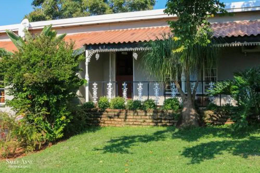 Singlestory house with a veranda surrounded by greenery and trees