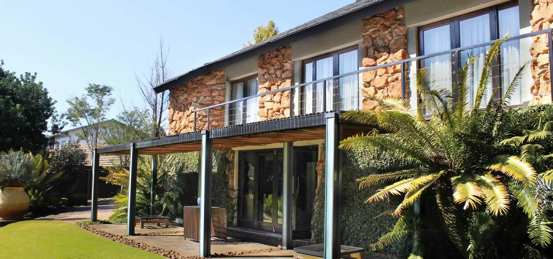 Modern house with large windows balcony and lush greenery in the garden