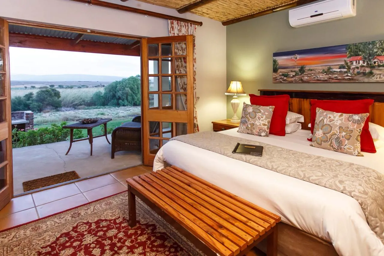 Bedroom with open patio doors view of countryside and a bench at the footboard