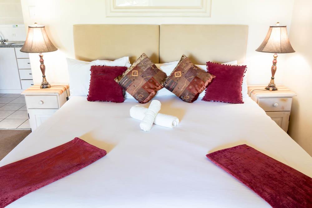 A neatly made bed with red and patterned pillows in a bedroom.