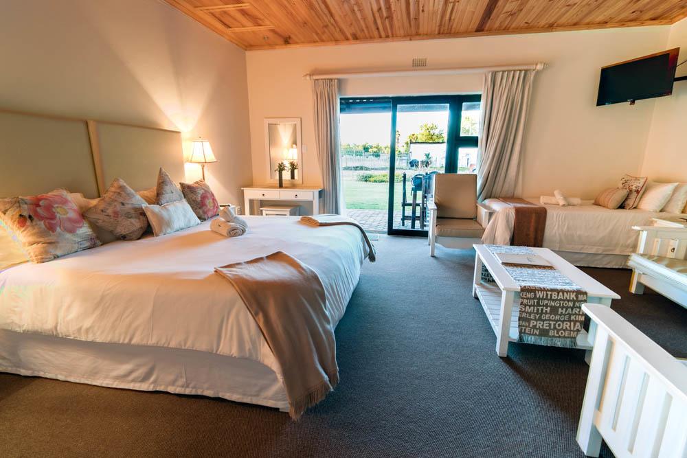 Cozy bedroom with large bed, armchair, and view of green field outside.