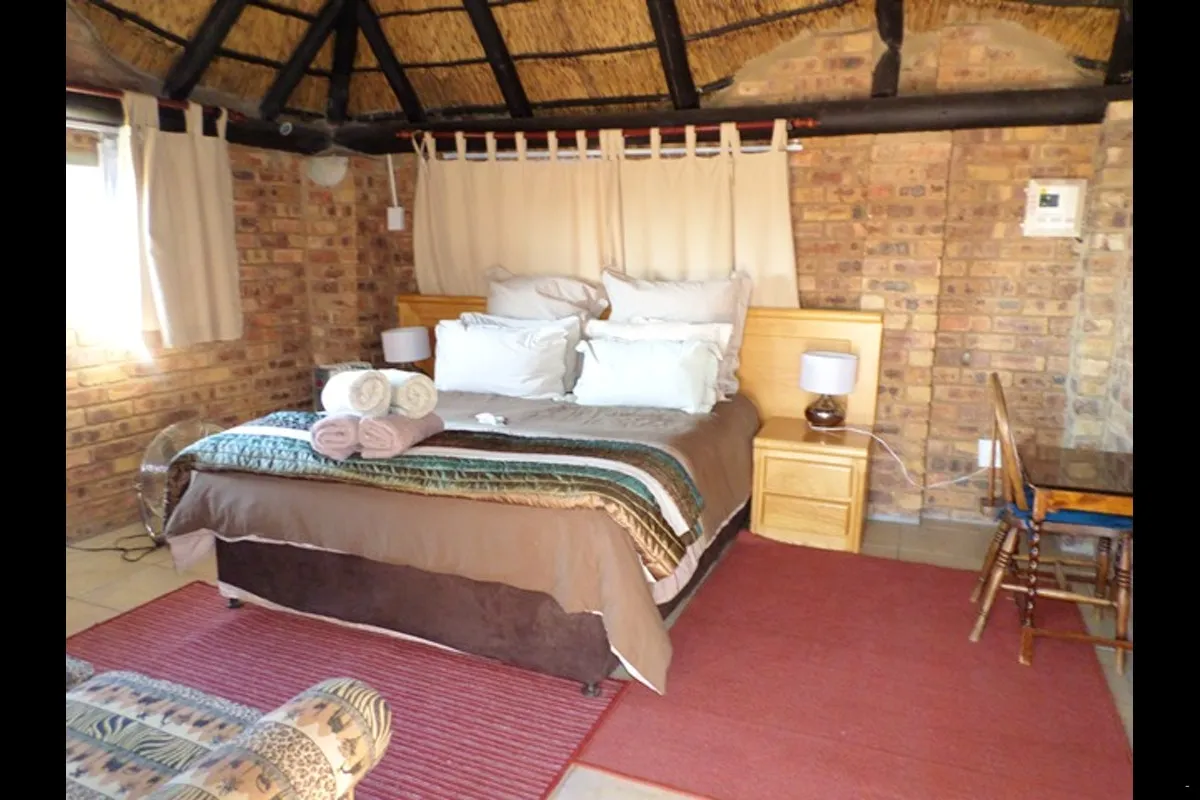 Cozy bedroom with a large bed brick walls and a thatched ceiling