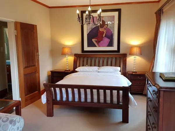 Wooden bed with white bedding in a cozy bedroom with a large wall art