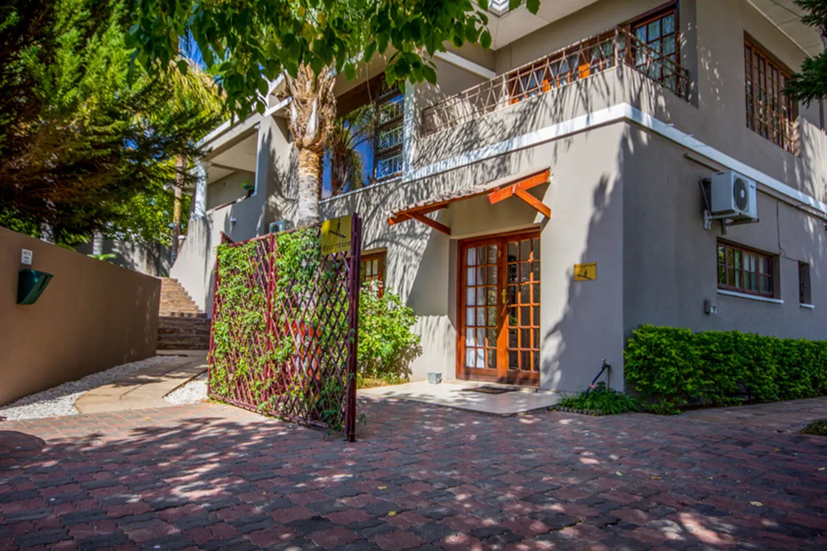 Twostory house with brick driveway wooden door and surrounding greenery