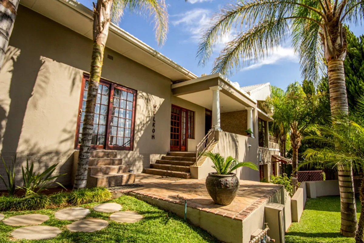 Modern house with large windows palm trees and a potted plant on porch
