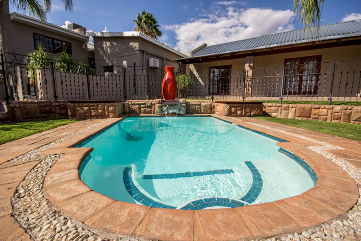 Swimming pool with a red sculpture in a garden setting