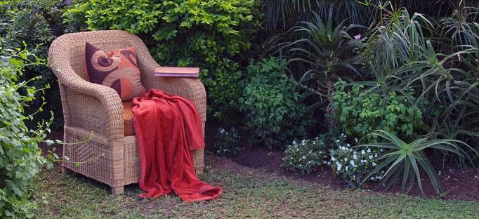Wicker chair with red blanket in a lush garden setting