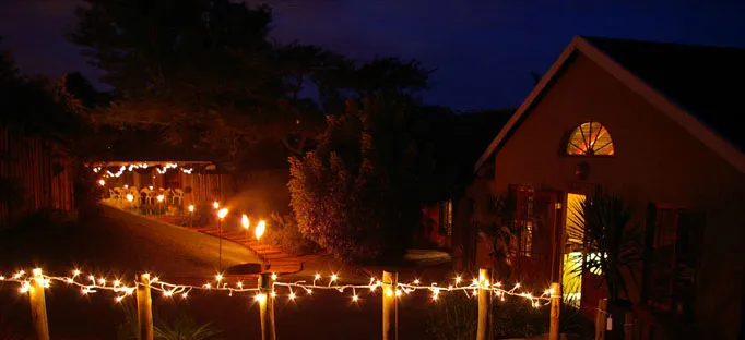 House at night with string lights and a lit pathway in the garden