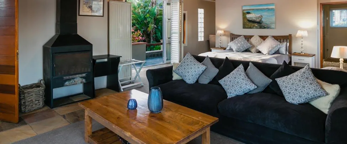 Cozy living room with black sofa wooden coffee table and bedroom in background