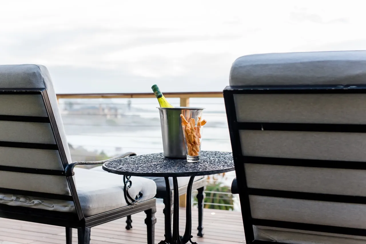 Two chairs and a table with a wine bottle and snacks on a patio