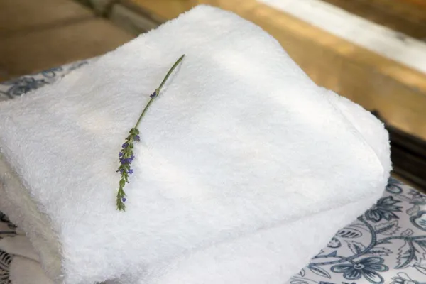 White towel with a sprig of lavender on a patterned surface