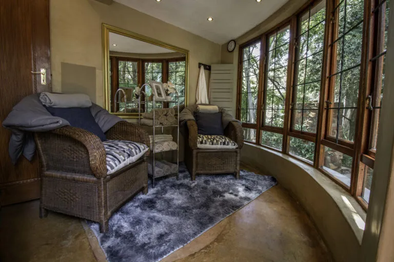 Cozy seating area with wicker chairs and large windows overlooking greenery