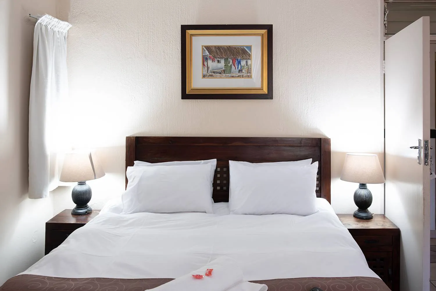 Neat bedroom with a large bed two bedside lamps and a framed picture