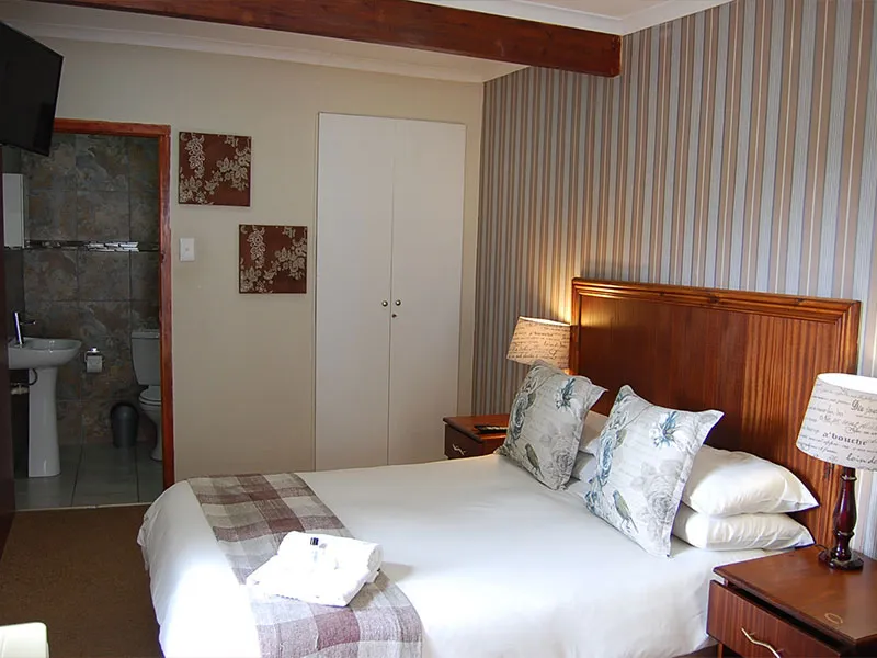 Bedroom with double bed striped wallpaper and adjacent bathroom