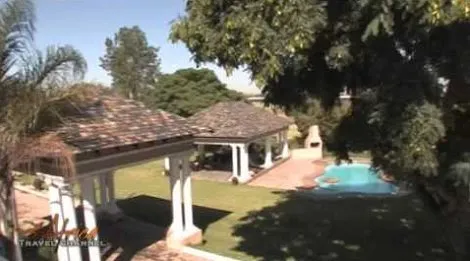Outdoor patio with pool trees and covered seating areas in a garden