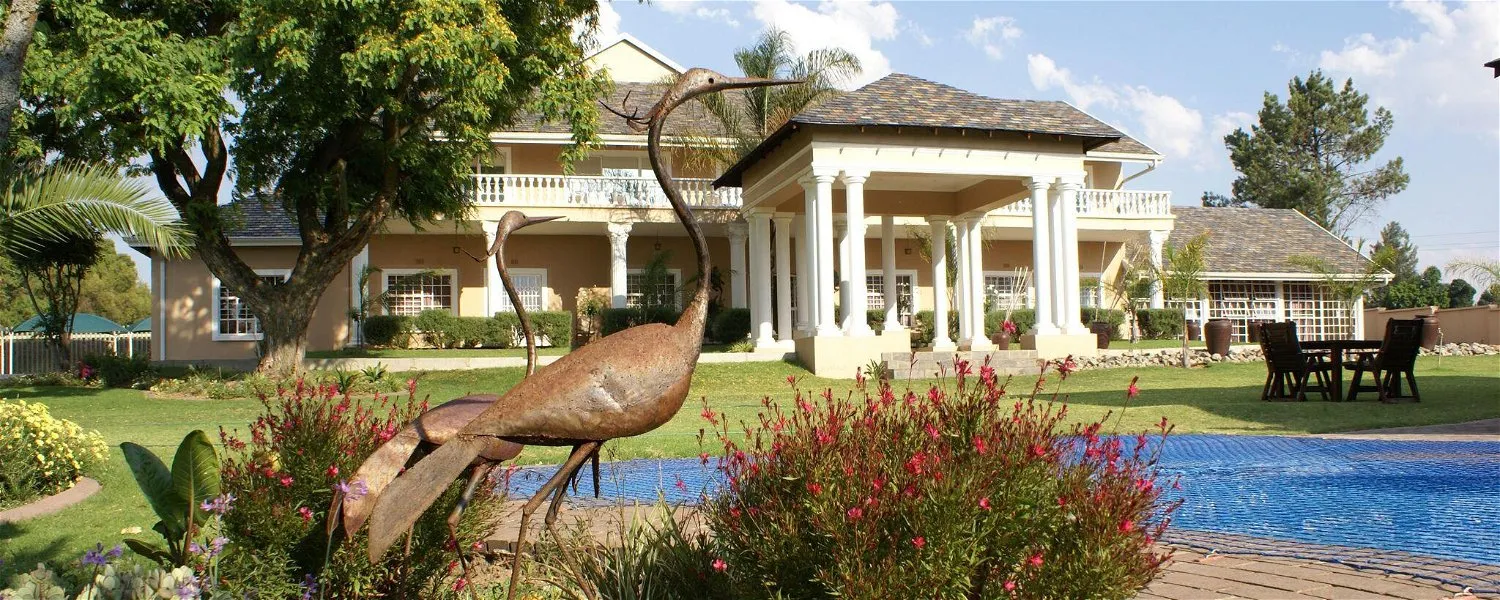 Large house with pool garden and bird sculpture in foreground